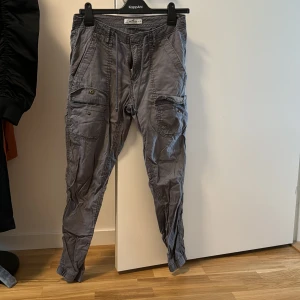 Cargo byxor Hollister Dam - Säljer mina gråa Cargobyxor från Hollister. Storlek 26, och man kan spänna de där uppe med hjälp av snören som finns i byxorna. 