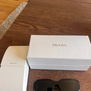 Prada solglasögon  - Hej!   Säljer mina Prada solglasögon då jag har köpt nya. Inga märken och är använda. Medföljer låda + extra till glasögonen, torkduk samt QR- kod för att visa dem är äkta.  Priset kan diskuteras vid snabb affär 