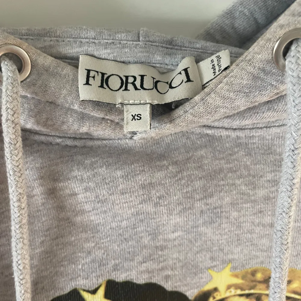 Grå fiorucci hoodie med det klassiska ängla trycket. Använd skick, se kragen på sista bild, men i övrigt inga fläckar! Pris kan diskuteras.. Hoodies.