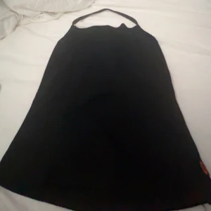 Svart topp med halterneck - Säljer en stilren svart topp med halterneck-design. Perfekt för en kväll ute eller en fest. Linnet är ärmlöst och har en enkel, elegant stil. Den är i nyskick och redo att bäras till nästa event! Oklart vart den är ifrån och vilken storlek men passar mig som har XS.