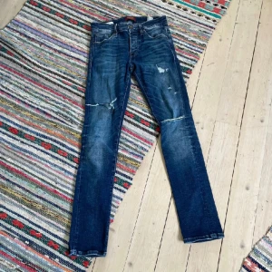 Blå jeans från Jack & Jones - Säljer dessa tvär snygga Jack n jones jeans med as sköna slitningar. Byxorna passar inte mig dessvärre och de är därför jag säljer.  Storlek 27/30 och är i 9/10 skick. Nypris 999 kr, mitt pris: 399, vid minsta fundering hör av dig! Jag är ca 175.