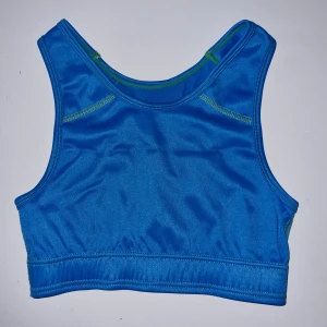 Blå ärmlös sporttopp - Säljer en blå sporttopp i syntetmaterial. Toppen har en tight passform och är perfekt för träning. Den har en enkel design utan några extra detaljer.
