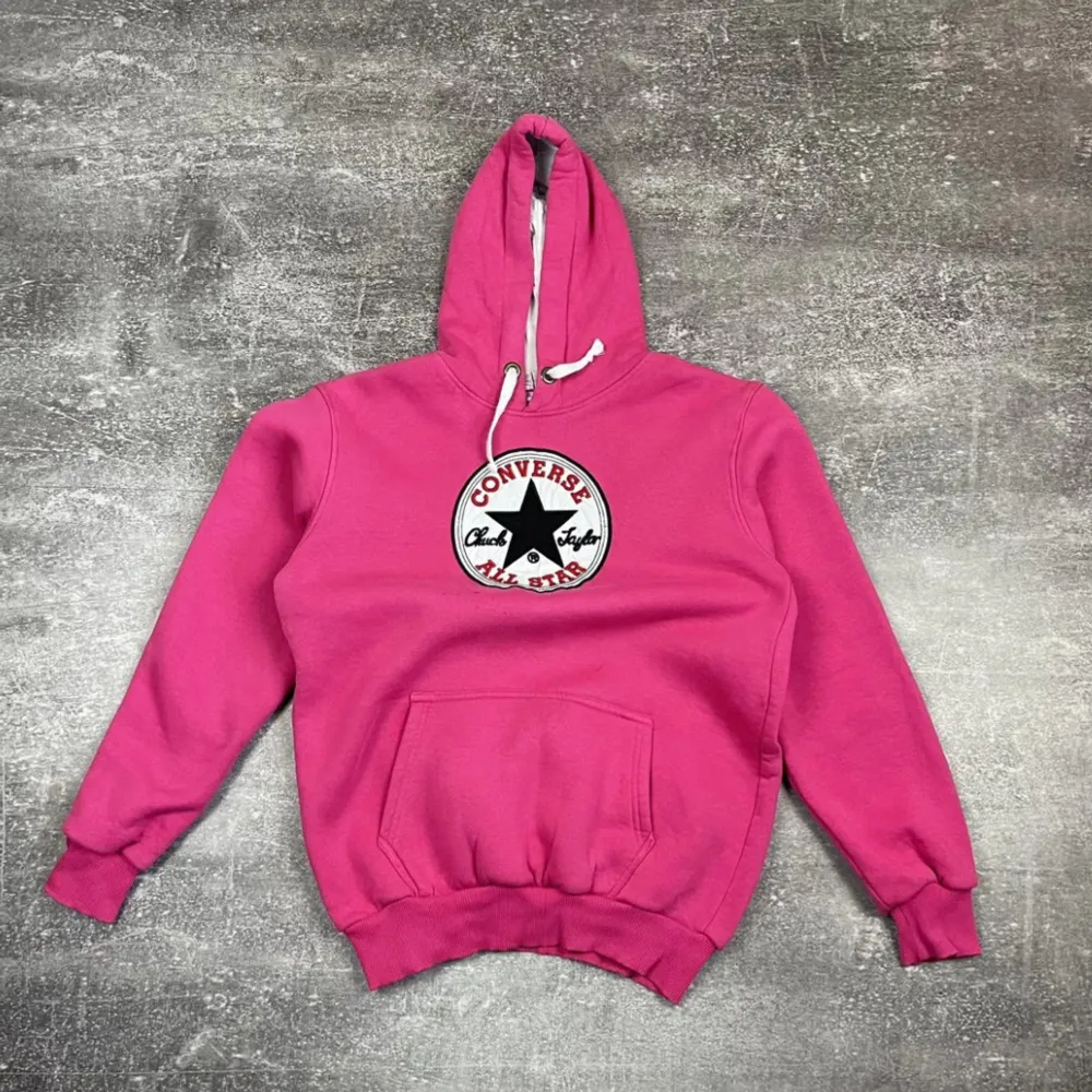 Säljer en supercool rosa hoodie från Converse med deras klassiska All Star-logga på bröstet. Den är perfekt för både chill och vardag, med en stor ficka fram och justerbar huva. Materialet är mjukt och skönt, perfekt för höst och vår!. Tröjor & Koftor.