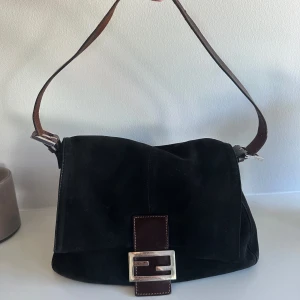 Fendi Baguette Mama - Säljer min älskade Fendi-väska i den perfekta modellen!✨  Det finns några sprickor i lädret på handtaget, men i övrigt är den i gott skick.  Mått: 28cm x 21cm x 11cm.  Metallplattan med ingraverad Fendi-logga ger äkthetsintyg