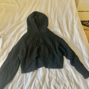 Svart stickad hoodie - Säljer en svart stickad hoodie med coola hålmönster. Den är croppad och har långa ärmar. Perfekt för en avslappnad stil och passar bra till höst och vår. Lite sliten men fortfarande snygg!