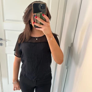 Svart blus med transparenta detaljer - Säljer en elegant svart tröja med transparenta detaljer upptill. Den är en enkel tröja men blir så speciellt med det coola upptill på tröjan. Tröjan är i storlek xs men den passar perfekt på mig som är i storlek s. Tröjan är helt ny! Kontakta mig om du har några frågor🤗💖