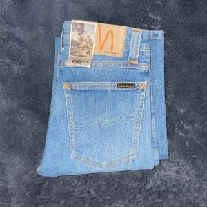 Blå jeans från Nudie Jeans - Snygga ljusblå jeans från Nudie Jeans med en klassisk femficksdesign. De har en skinny passform och är tillverkade i ett mjukt denimtyg. Perfekta för en stilren look. Helt nya! (Bilderna är inte mina de är från mella shops)