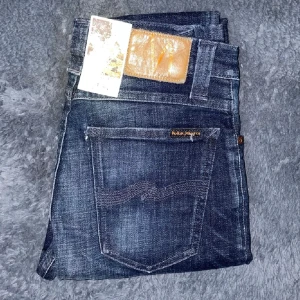 Mörkblå jeans från Nudie Jeans - Snygga mörkblå jeans från Nudie Jeans med en klassisk femficksdesign. De har en smal passform och är tillverkade i högkvalitativt denim. Perfekta för en stilren look. Helt nya! (Bilderna är inte mina de är mella shops)