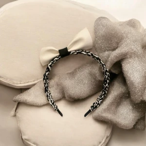 Svartvitt diadem med rosett - Snyggt diadem i svartvitt, som är knuten med makramé. Med en elegant beige rosett på sidan av konstläder. Perfekt för att ge en stilfull touch till din outfit.