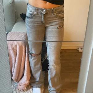 Grå jeans med slitningar från ginatricot - Snygga grå jeans från Ginatricot med slitningar på knäna och låren. De har en klassisk femficksdesign och en knappgylf. Perfekta för en avslappnad stil. Klippt hålen själv! 