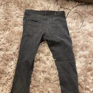 Svarta jeans från Tiger of Sweden - Snygga svarta jeans från Tiger of Sweden med klassisk femficksdesign och knappgylf. Perfekta för en stilren look. Tillverkade i Turkiet.