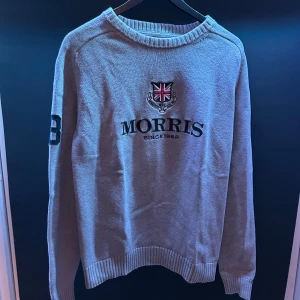 Grå tröja från Morris - Tja, säljer en stilren grå tröja från Morris med broderad logga och Union Jack på bröstet. Tröjan har långa ärmar med siffran 68 på ena ärmen och ribbade muddar vid ärmslut och nederkant. Perfekt för en avslappnad stil. Tveka inte på att höra av er vid funderingar🥂