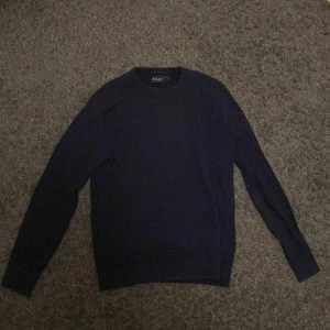 Mörkblå tröja från Riley - Säljer en stilren mörkblå tröja från Riley. Den är långärmad och har en klassisk rund halsringning. Perfekt för kyligare dagar och kan enkelt matchas med olika outfits.ny skick
