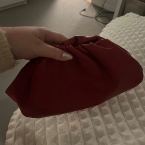Röd kuvertväska  - Snygg röd kuvertväska. Lädret har gått upp lite på insidan av väskan, men inget som syns när den är stängd.