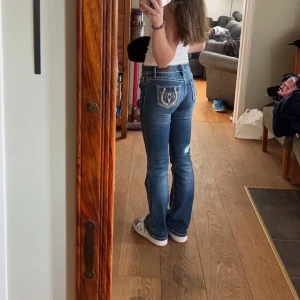 Blå bootcut jeans - Snygga blå bootcut jeans med dekorativa bakfickor. De har en lågmidjad passform och är perfekta för en avslappnad stil. Jeansen har en klassisk femficksdesign och en lätt tvättad look. Storlek 12 men är lika stora som W24,  Passar mig som har XS/32, Reglerbara i midjan, Passar nån upp till 160, Knappt använda, Nypris 1300, Kostar 1500 i vuxenstorlek.