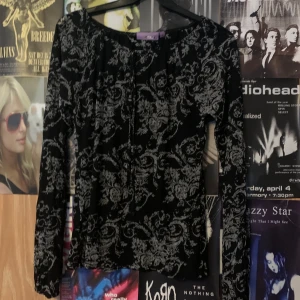 Svart och grå blommig topp från Zoul - Snygg svart topp från Zoul med grått blommönster. Toppen har långa ärmar och en rund halsringning. Perfekt för en stilren look.