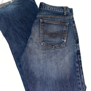 Blå jeans från Blend - Snygga blå jeans från Blend med klassisk femficksdesign och subtila slitningar för en cool look. De har en knappgylf och bälteshällor, perfekt för en avslappnad stil.Sitter bra på mig som har storlek 36. Dom är mellan low och mid waist skulle ja säga. 