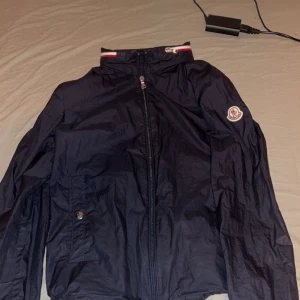 Svart vindjacka från Moncler - Säljer en stilren mörkblå äkta moncler vindjacka som är storlek XS och är ifrån Moncler ny pris 5500. Jackan har ett Moncler-märke på ärmen och en praktisk ficka med knapp. Perfekt för svala dagar. Ni får ge egna förslag på pris