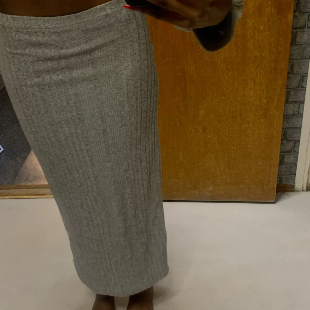 Snygg grå ribbad kjol i tight passform. Kjolen är lång och perfekt för en stilren look. Den är gjord i ett mjukt och stretchigt material som formar sig fint efter kroppen.. Hameet.