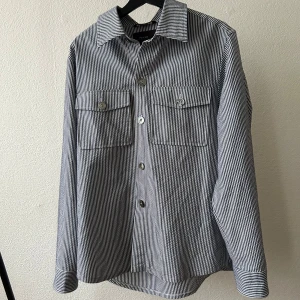 Randig overshirt från Oscar Jacobson - Snygg randig overshirt i blått och vitt från Oscar Jacobsson i nästan nyskick, ordinarie pris 2900kr. Storlek 50 motsvarar större M/L