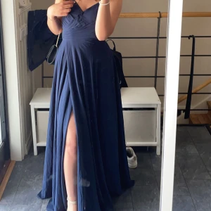 Mörkblå balklänning med öppen rygg - Säljer en elegant mörkblå klänning från JJs House. Klänningen har en vacker öppen rygg med snörning och tunna axelband. Perfekt för speciella tillfällen.  Vi sydde upp vid bröstet men vi har öppnat den. Klänningen kostade ungefär 1400. Klänningen har använts en gång jag är 163 ni kan se hur längden ser ut på bilderna. Du kan även justera hur tajt du vill ha den med hjälp av rygg snören ! Perfekt till bal då den inte väger så mycket. Tunn material på överdelen och sedan lite tjockare vid ändan. 