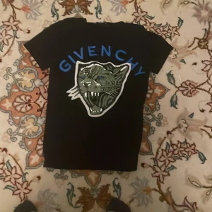 En svart Givenchy tröja  - En svart T-shirt som det är en panter på framsidan som gapar. Över pantern sa står det givenchy i blåa bokstäver.