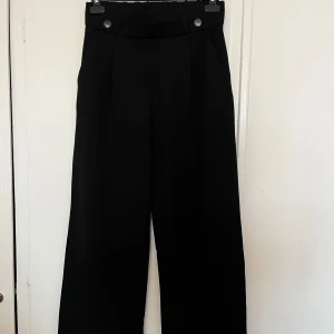Svarta byxor från Only - Snygga svarta byxor från Only med hög midja och vida ben. Byxorna har dekorativa knappar i midjan och en stilren design som passar perfekt för en chic look 💕