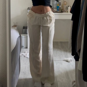 Beige linnebyxor med resårmidja - Snygga och bekväma beige linnebyxor med resårmidja och snörning. Byxorna har en loose passform och är perfekta för en avslappnad stil. De har praktiska fickor baktill och är tillverkade i ett lätt och luftigt material.