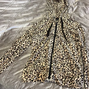 Leopardmönstrad tröja från Gina Tricot - Säljer en leopardmönstrad tröja från Gina Tricot i storlek XS. Tröjan har en dragkedja framtill och en luva. Perfekt för att ge din outfit en djärv touch 🐆
