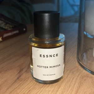 Essnce Hotter Mimosa Eau de Parfum - Säljer en flaska Essnce Hotter Mimosa Eau de Parfum. Flaskan är genomskinlig med en svart kork. Ska dofta som Linn Ahlborgs hotshot, påminner mycket om Sí från Armani. Syns på bilden hur mycket som är använt, 50ml. Förvarad mörkt och kallt.