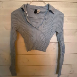Ljusblå ribbad omlottopp från Hm - Säljer en ljusblå ribbad omlottopp från HM. Toppen har en croppad design med långa ärmar och en v-ringad hals. Perfekt för en stilren och modern look. Passar bra till både jeans och kjol. 💙Den skulle behöva strykas innan användning😅 Storlek xxs men jättestretchig så passar xs också
