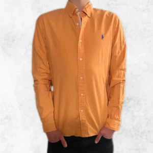 Orange Ralph Lauren skjorta - Säljer denna riktigt snygga orange skjortan från Polo Ralph Lauren. Den är i slimfit och i ny skick då den bara har används ett fåtal gånger. Säljer även två andra likande skjortor i min profil. Denna tröjan säljs för ca 2000 kr ny men vi säljer den för endast 149 kr. Vid några frågor eller funderingar är det bara att höra av sig.