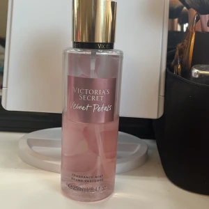 Victoria's Secret Velvet Petals Fragrance Mist - Säljer en Victoria's Secret Velvet Petals Fragrance Mist. Flaskan är rosa med en gyllene kork och rymmer 250 ml. Doften har inslag av frodiga blommor och mandelglasyr, perfekt för en fräsch och blommig känsla. Lite mer än halva kvar