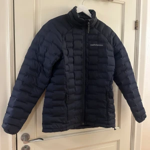Svart dunjacka från Peak Performance - Säljer en svart dunjacka från Peak Performance. Jackan har en quiltad design med dragkedja framtill och hög krage. Perfekt för kyliga dagar med stil och komfort. 🖤Storlek S, modell Argon light jacket herr.