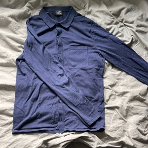 Mörkblå kofta/cardigan från Selected Homme - Snygg mörkblå kofta/cardigan från Selected Homme i ekologiskt material. Skjortan har långa ärmar och en klassisk krage med knappar framtill. Perfekt för en stilren look. Nästan som ny utan skavanker. Den är lite loten i storlek så den skulle även passa nån som jag storlek S.
