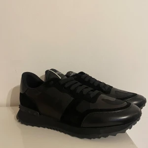 Valentino rock rummets - Säljer ett par helt nya Valentino Garavani sneakers i svart camo. Stilren och exklusiv design med detaljer i mocka och läder samt de ikoniska nitarna vid hälen.  Detaljer:  Storlek: 44 (passar 43)  Färg: Svart/Camo  Material: Läder, mocka och textil  Inkluderar extra skosnören  Ingen originalbox medföljer  Perfekta för dig som vill ha en snygg och trendig sneaker med hög komfort!  Pris: 1749kr Skickas eller möts upp enligt överenskommelse.  Skicka PM vid intresse!
