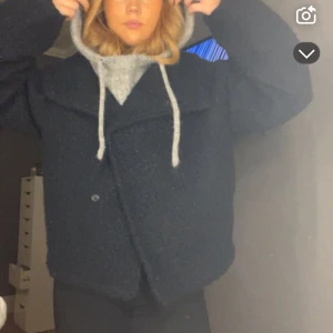 marinblå teddyjacka - Mysig marinblå teddykappa med oversized passform. Jackan har en stor krage och knappar framtill. Perfekt för kyliga dagar när du vill hålla dig varm och stilren.