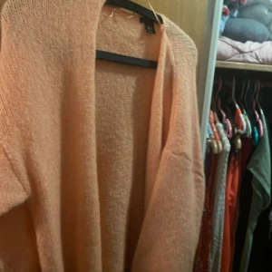 Populär prikosfärgad stickad kofta från Lindex - Mysig kofta från Lindex. Koftan har en öppen design utan knappar och långa ärmar.