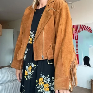 Vintage mockajacka med fransar - Vintage brun mockajacka med fransar längs ärmarna och ryggen, vackert foder. Modellen är oversized och passar nog strl 36-40 bäst. Märke okänt. 