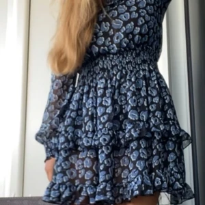 Svartblå leopardmönstrad klänning  - Säljer denna underbara klänning som inte längre säljs! Så fin skärning runt halsen och vackra volanger. Skönt material och i super skick.