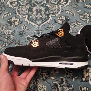 Svarta och guldiga Nike Air Jordans - Säljer ett par snygga Nike Air Jordans i svart med guldiga detaljer. Skorna har en klassisk design med snörning och en vit sula som ger en cool kontrast. Perfekta för både vardag och fest! 🖤✨ Pris kan diskuteras