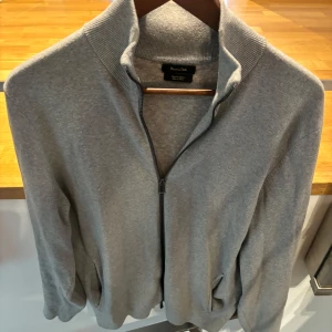 Grå kofta med dragkedja - Säljer en stilren grå kofta från Massimo Dutti. Den har en normal passform och är perfekt när som helst. Tröjan sitter bra men är ganska rak i passformen. Nypris 800. 