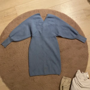 Blå stickad klänning - Mysig blå stickad klänning med v-ringad hals och långa ärmar. Perfekt för kyliga dagar och kan stylas både upp och ner. Den har en bekväm passform som är både snygg och praktisk. Priset går att diskuteras🩷