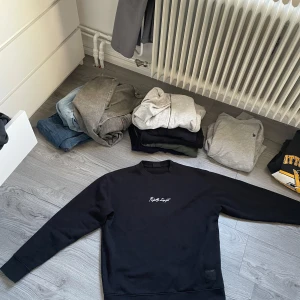 Sweatshirt från Pull & Bear - Säljer en svart sweatshirt från Pull & Bear med en snygg text broderad på framsidan. På baksidan finns ett coolt tryck av en byggnad. Tröjan är långärmad och perfekt för både höst och vår. Den är i mycket bra skick och passar till en avslappnad stil.