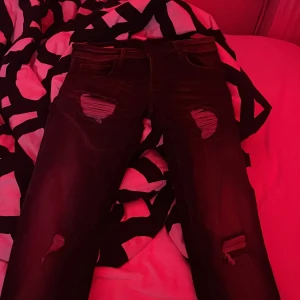 Svarta jeans med slitningar - Säljer ett par svarta jeans från The Denim Journey i storlek 31/32.gjorda av MaxStretch-material för extra komfort. Jeansen har coola slitningar på framsidan som ger en edgy look. Perfekta för både vardag och fest!