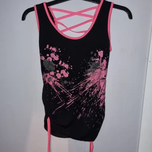 Svart och rosa linne från FunkyFit - Snyggt svart linne från FunkyFit med rosa detaljer och coolt mönster framtill. Linnet har korsade band i ryggen.