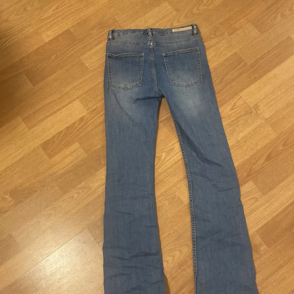 Säljer ett par snygga blå jeans från LAB Industries. Som är i storlek 170.De är i bra skick och har en klassisk femficksdesign. Jeansen har en bootcut-stil och är perfekta för både vardag och fest. De är tillverkade i ett bekvämt denimtyg som sitter skönt hela dagen.. Jeans & Byxor.