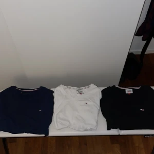 T-shirts från Tommy Hilfiger - Säljer tre snygga t-shirts från Tommy Hilfiger i olika färger: marinblå, vit och svart. Alla har en liten broderad logga på bröstet och är i normal passform. Perfekta för både vardag och fest! De är i mycket bra skick och gjorda av mjuk bomull. Den vita och mörkblåa tröjan är i storlek M och den svart är i storlek L.
