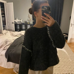 Mörkgrå stickad tröja från Mulaya - Säljer en supermysig mörkgrå stickad tröja från Mulaya. Den har en loose passform och långa ärmar med coola vita detaljer längs sömmarna. Perfekt för höst och vinter när du vill hålla dig varm och stilren. 🖤