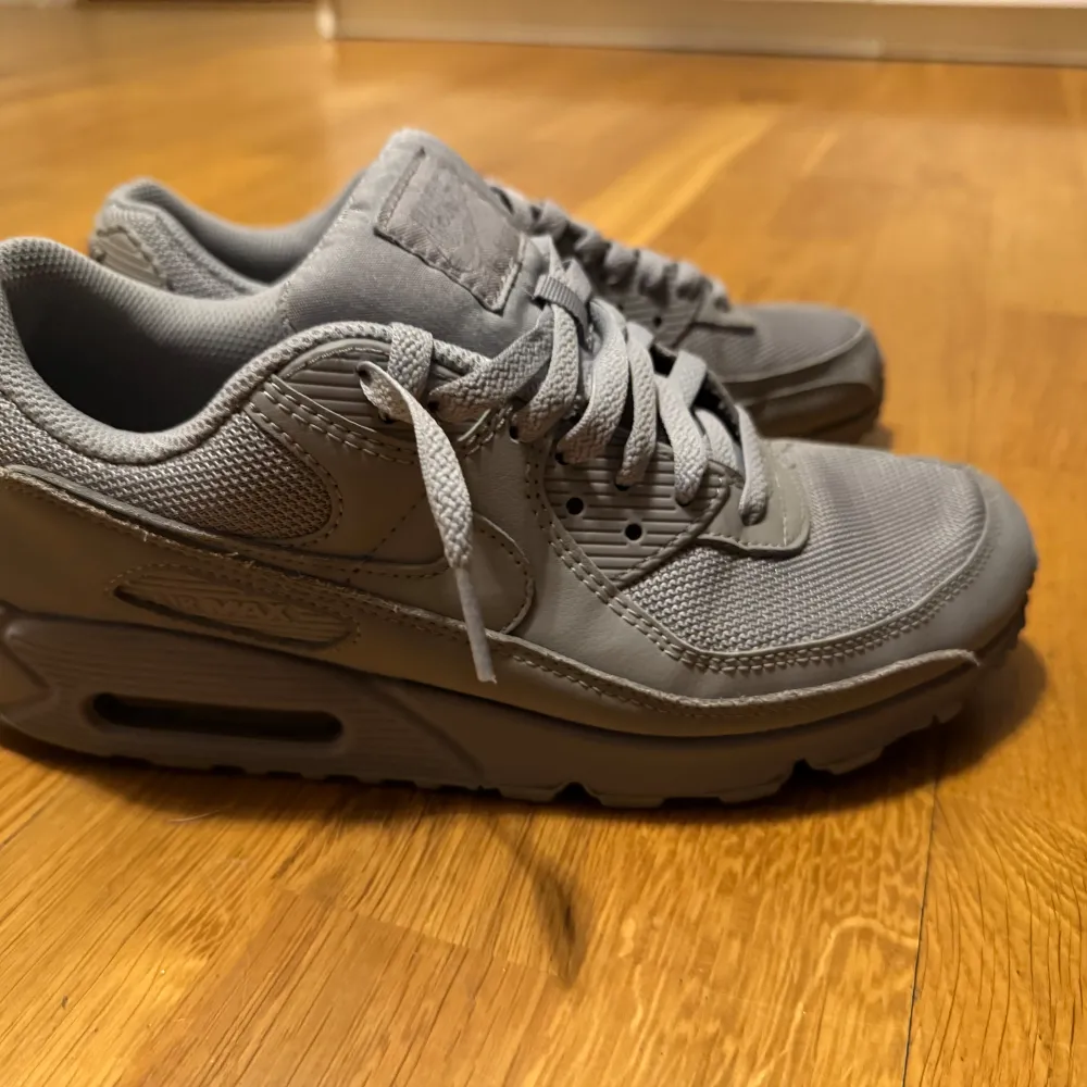 Säljer ett par grå Nike Air Max sneakers i mycket bra skick. De har en klassisk design med snörning och en bekväm sula som ger bra dämpning. Perfekta för både vardag och träning. Storlek är inte specificerad, men de ser ut att vara i herrstorlek.. Skor.